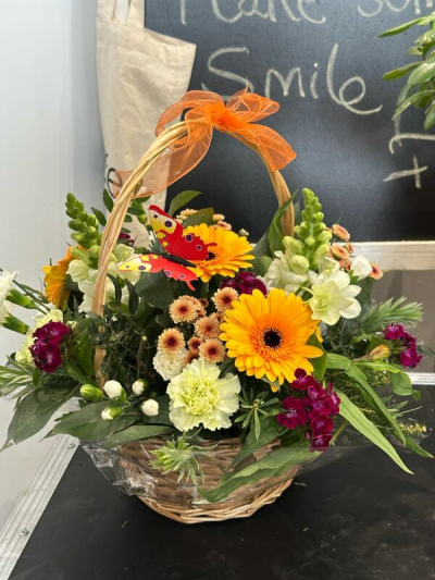 Joyful Wishes - A cheerful basket arrangement in vibrant yellow, orange and rich purple tones, beautifully arranged with seasonal flowers to brighten any occasion.