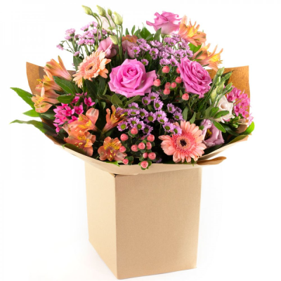 Peach Petals - A cheerful wrapped bouquet in soft pink, peach and coral tones, complemented by fresh greenery.